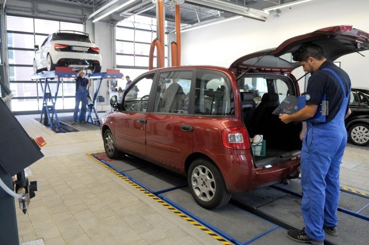 TÜV NORD Prüfer Sachverständiger kontrolliert die Warnweste und das Warndreieck im Auto